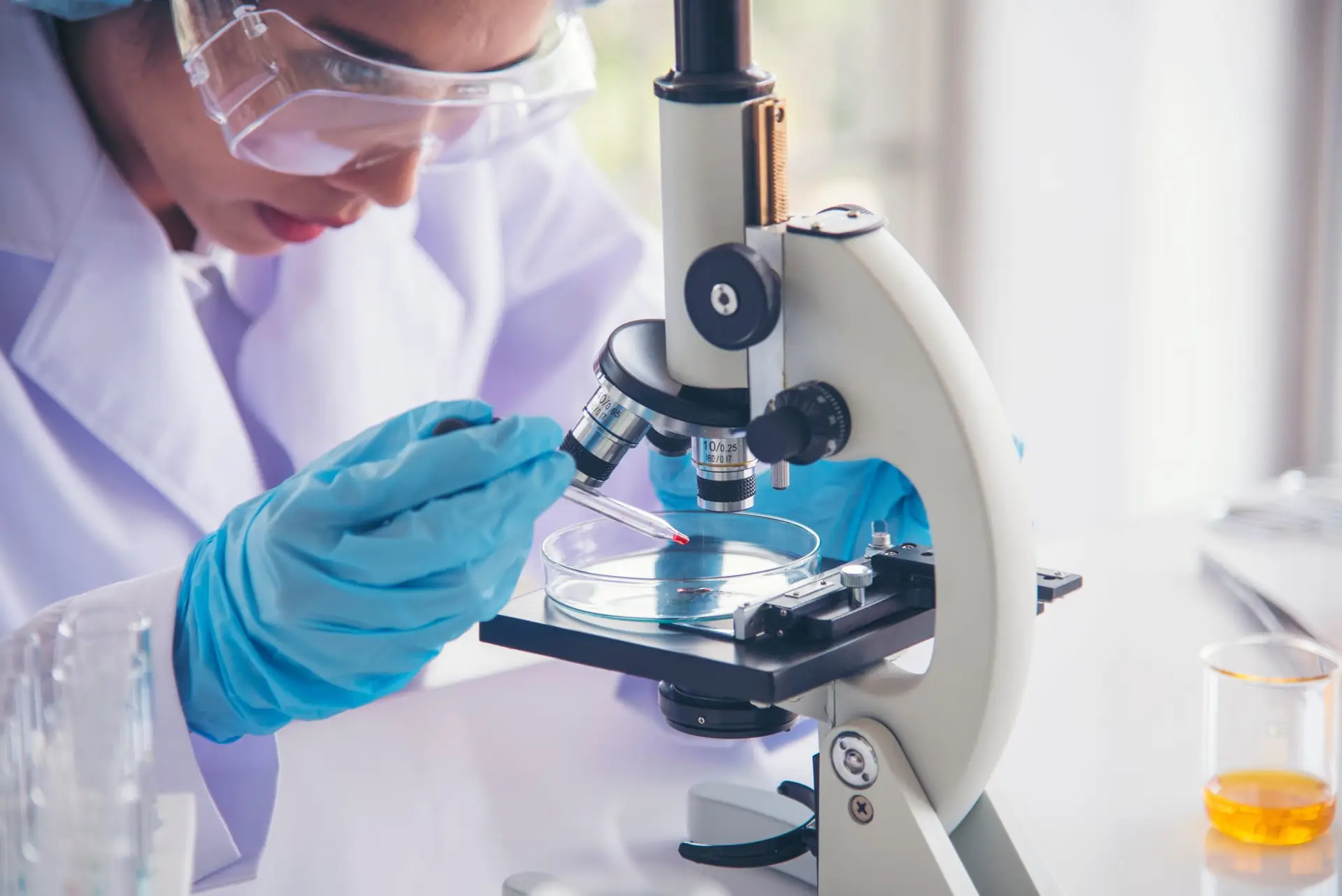 Woman scientist in lab look at science microscope medical test a